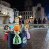 Muñecas Xiquetes Falleres en la emblemática Plaza de la Virgen de Valencia, representando la tradición fallera con trajes y peinados típicos. Hechas con materiales biodegradables y personalizables.